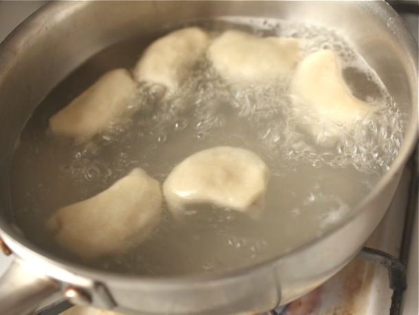 Homemade dumplings boiling in a pan of water.