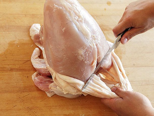 Using a boning knife to help remove stubbornly stuck portions of turkey skin on a bone-in whole turkey breast.