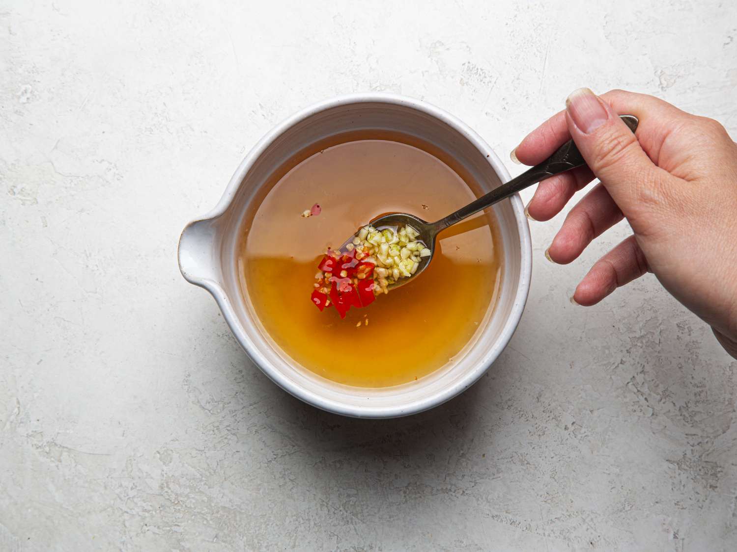 Overhead view of adding garlic and chiles to vingear