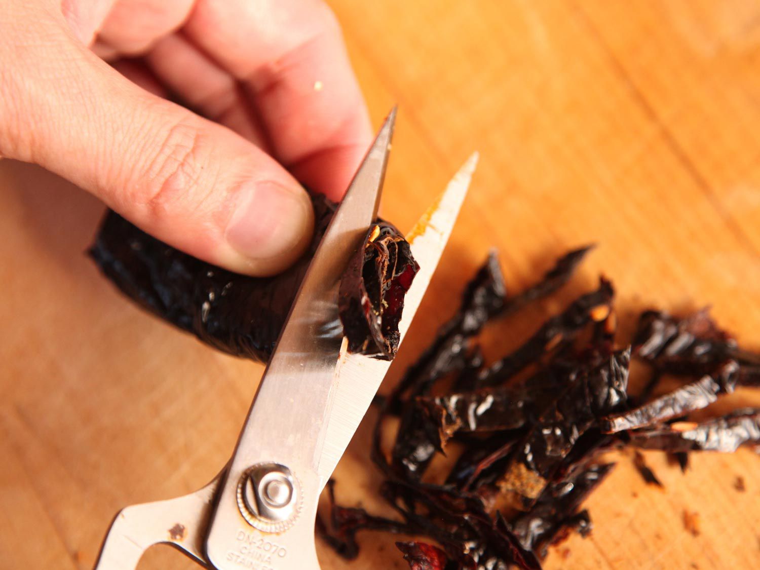 Cutting dried chiles into small pieces with kitchen shears. 