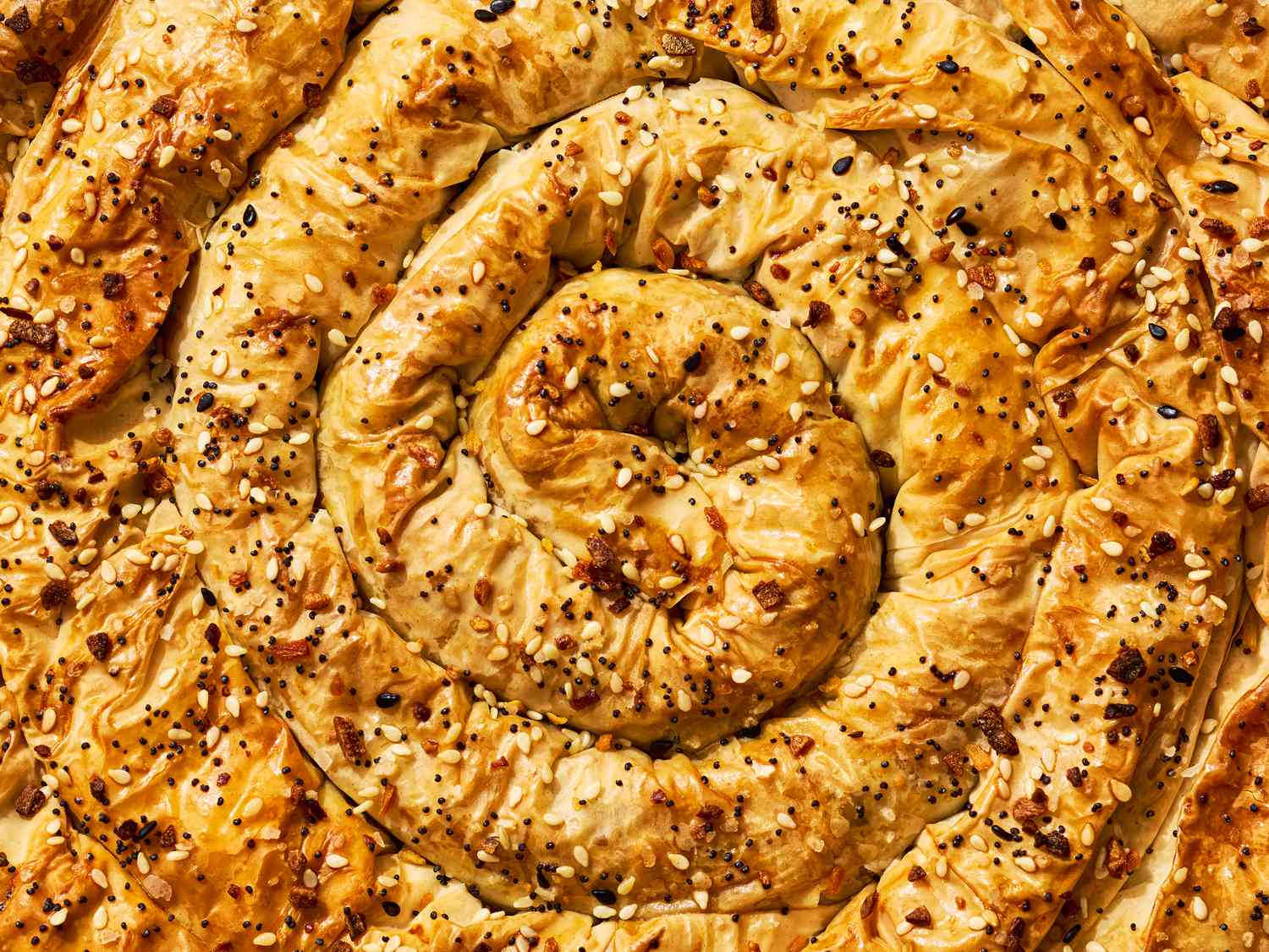 A spiral-shaped borek pastry topped with sesame and other seeds