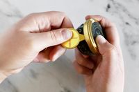 Hands opening a Caviar Co jar of caviar using a caviar tin key opener