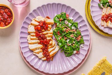 A plate of sliced pork chops with strawberry balsamic glaze and a side of spinach salad