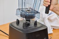 A hand lifting the Vitamix Ascent X2 jar from its base