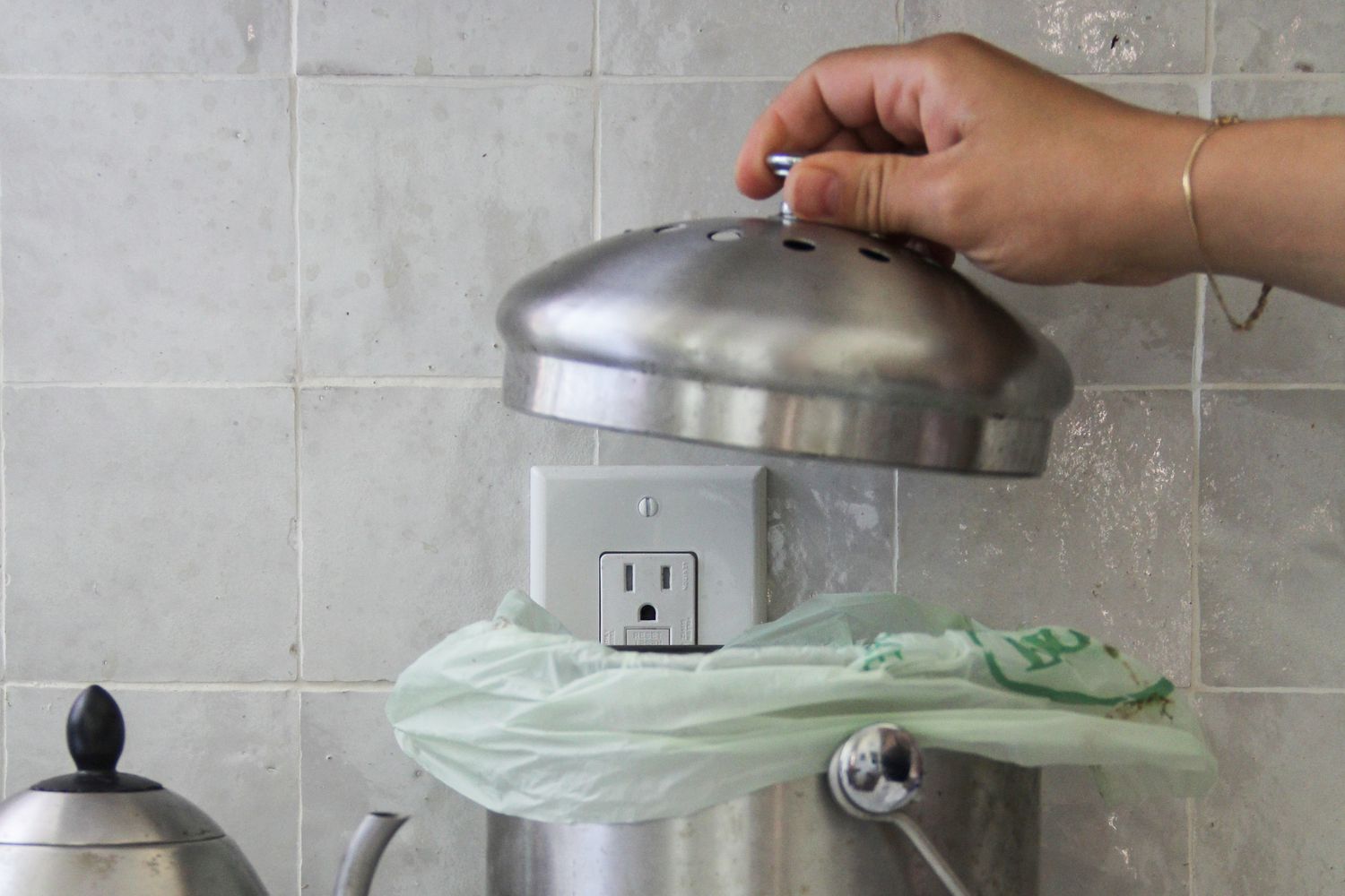 A hand lifting the top off the Epica countertop compost bin