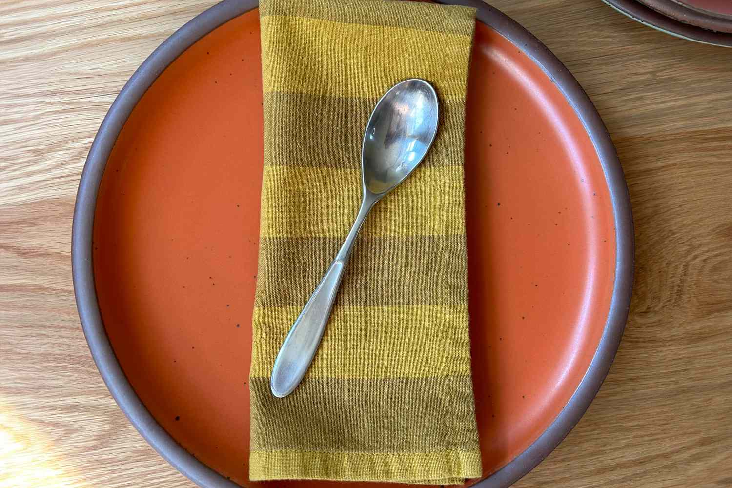 Yellow stripe cloth napkin on top of a orange plate
