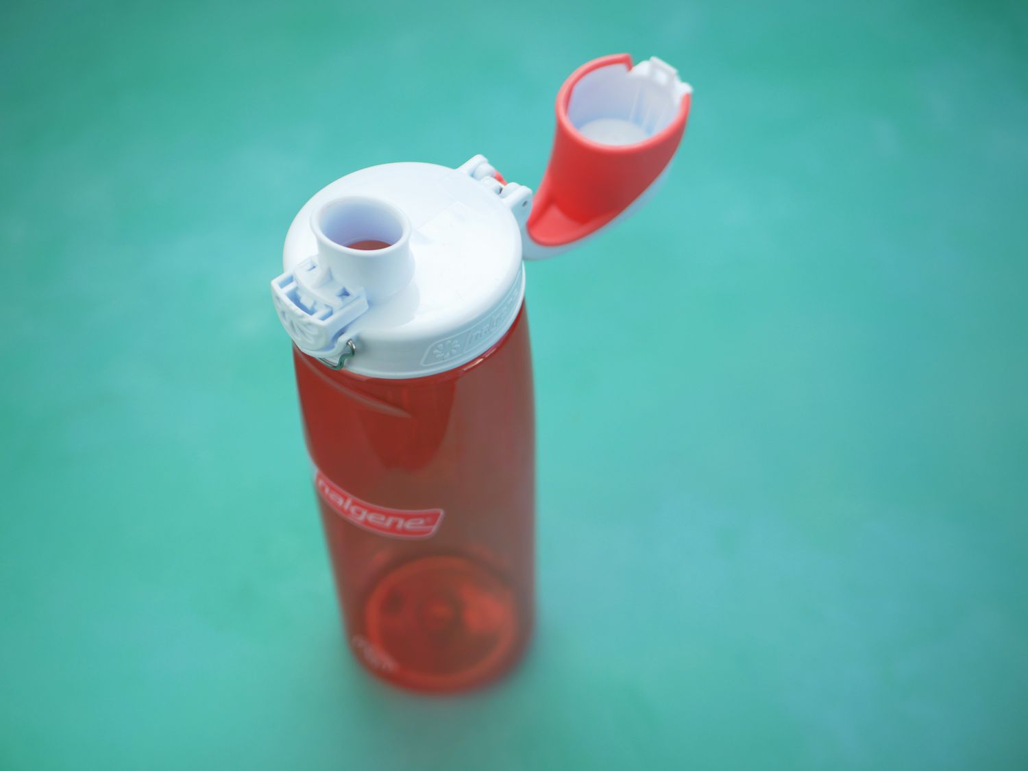 pink nalgene water bottle with the lid open on a blue green surface