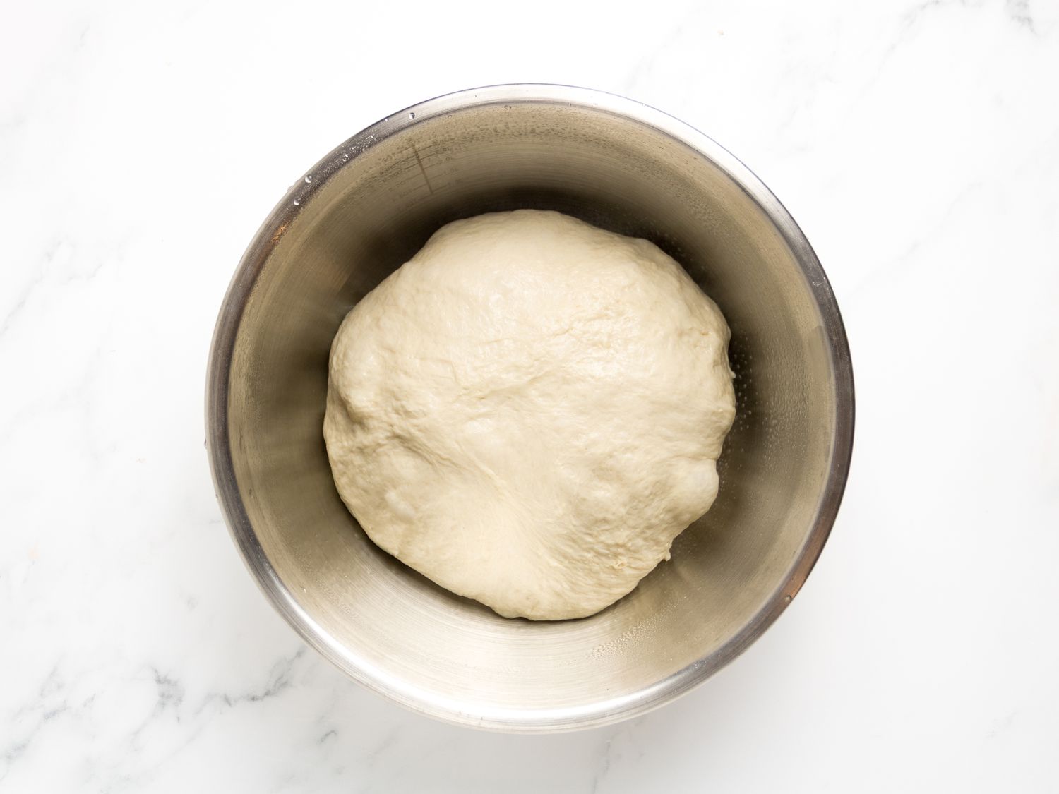 A bowl containing a ball of dough on a countertop