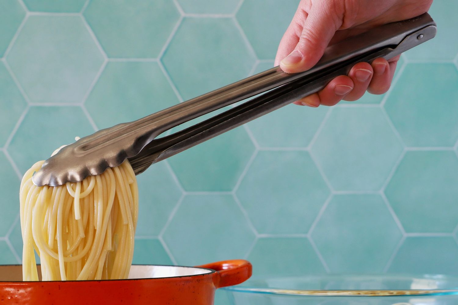 A person using the Winco Stainless Steel Tong to pick up pasta