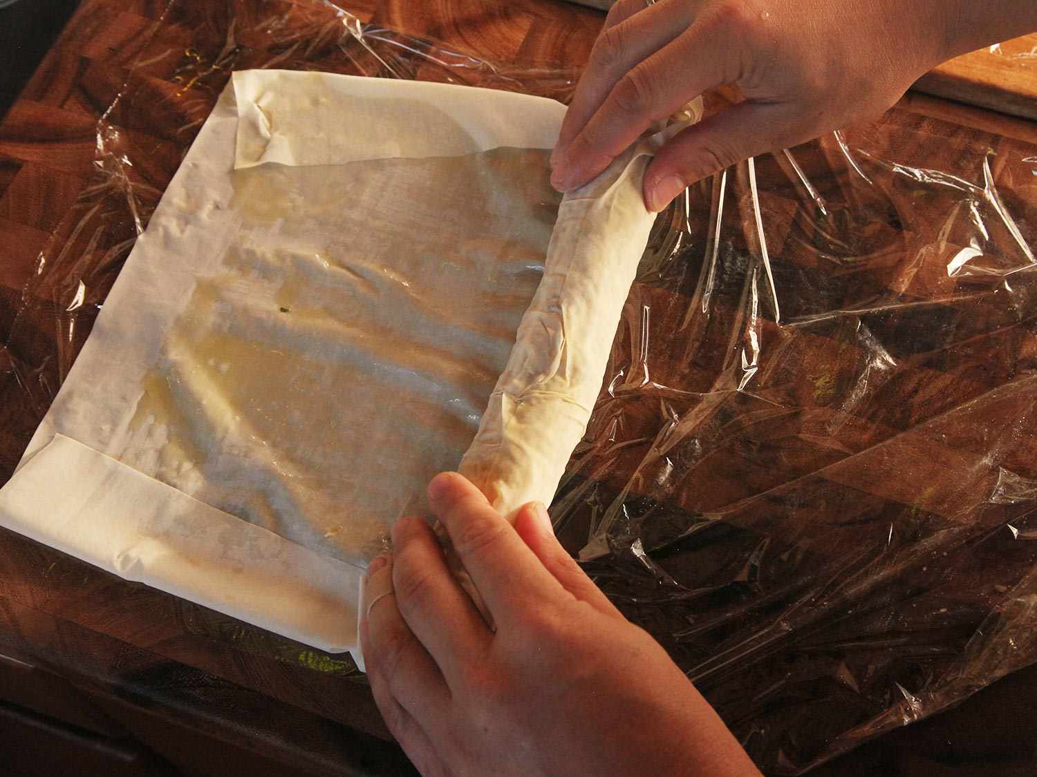 Rolling filled phyllo sheet with folded sides.