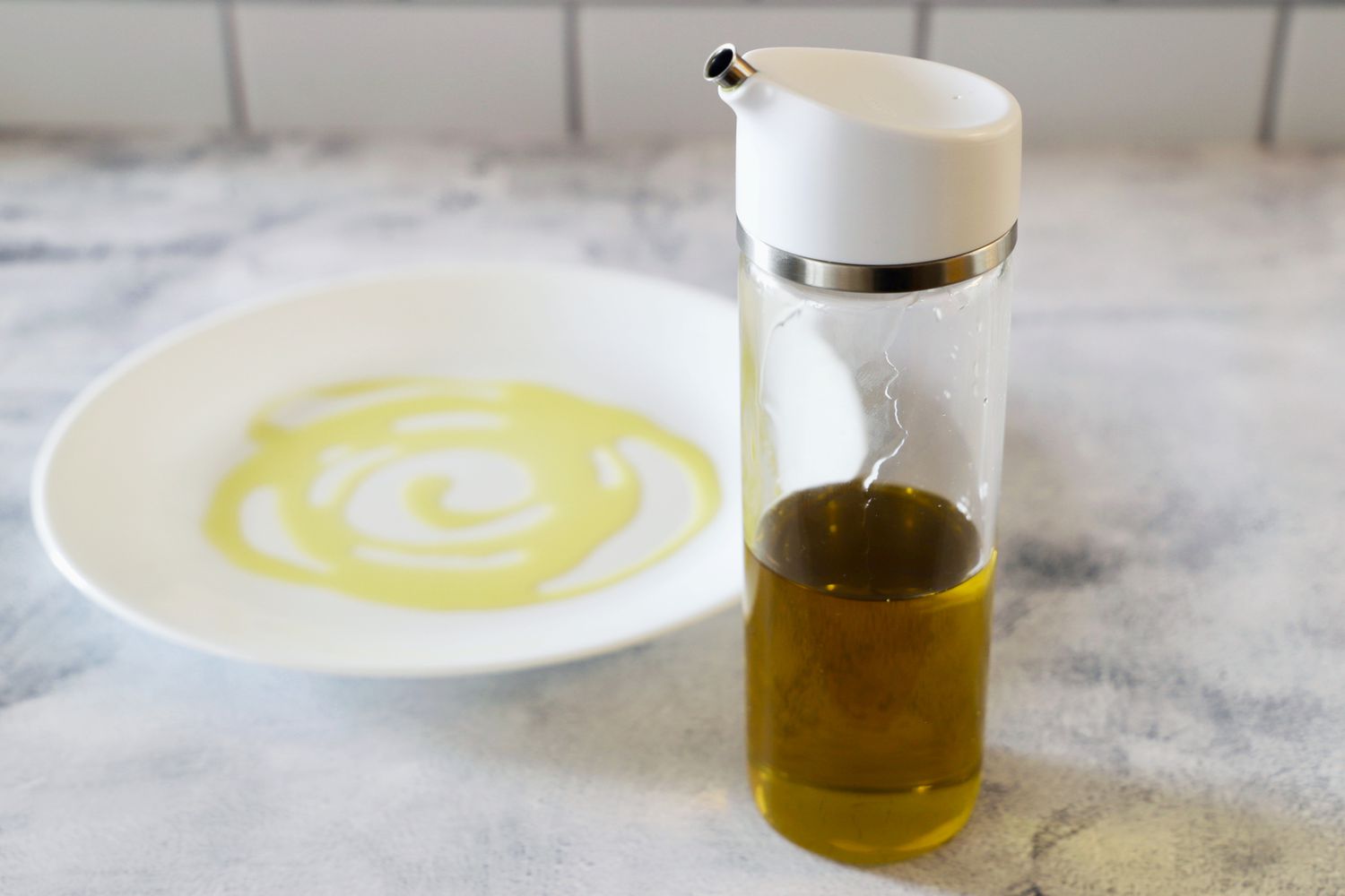The OXO Precision Pour Glass Dispenser next to a dish with oil