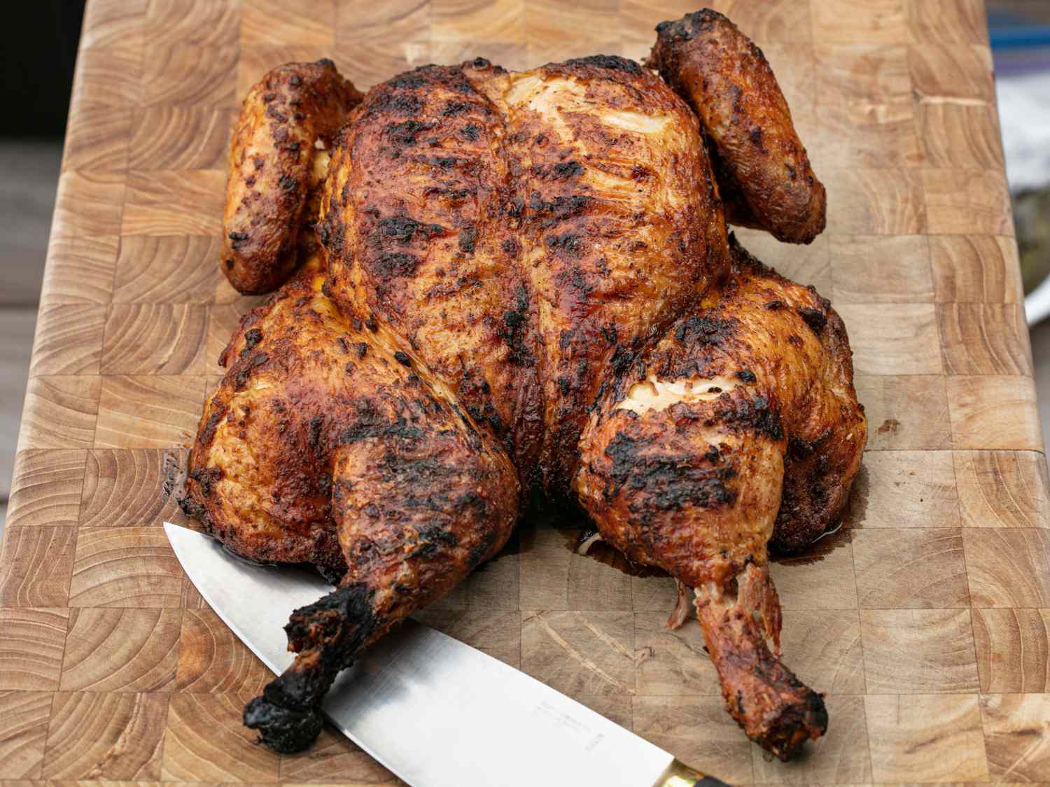 Whole grilled Peruvian-style chicken resting on cutting board before carving.