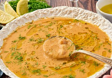 A bowl of chickpea stew garnished with herbs and oil served in a decorative plate