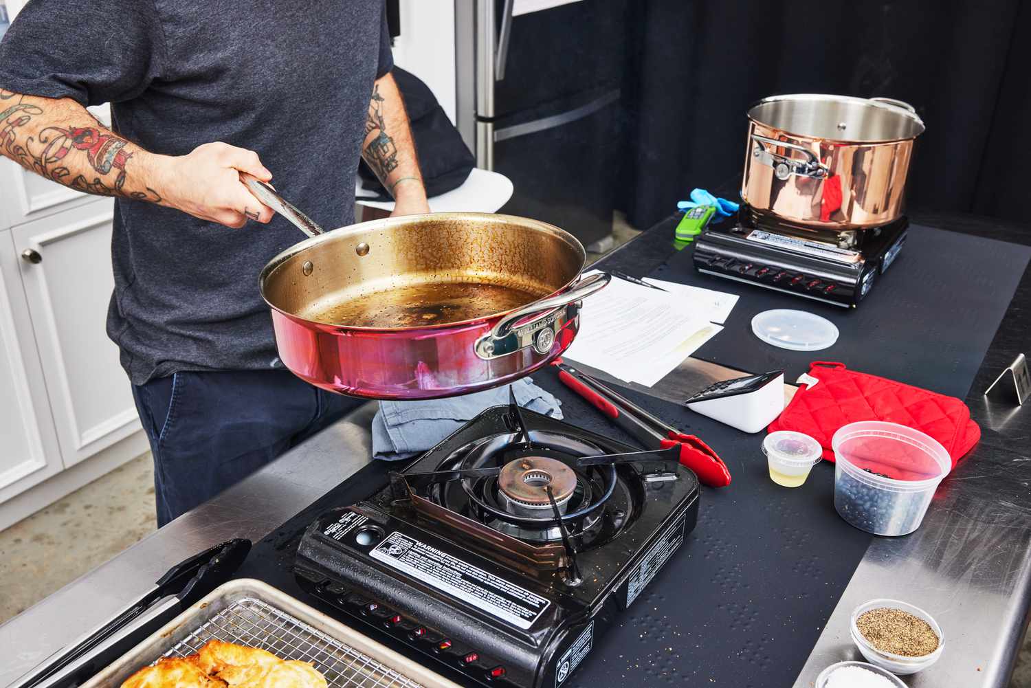 Hand holding Williams Sonoma Thermo-Clad Copper 10-Piece Cookware Set pan over a burner