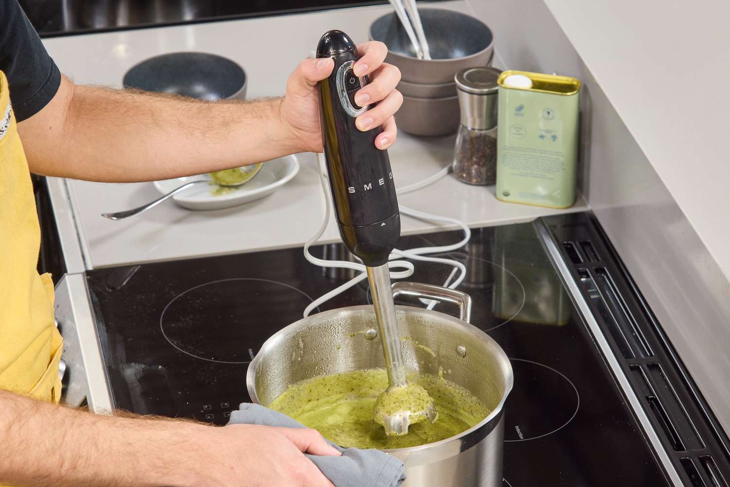 A person uses the Smeg Hand Blender to make soup