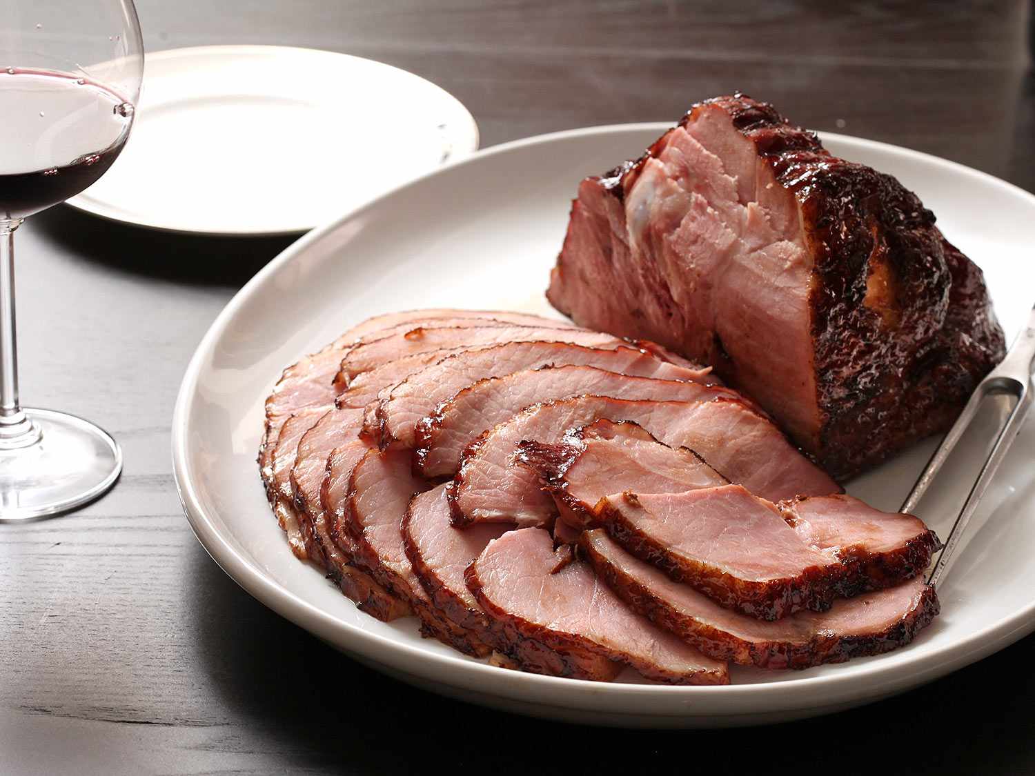 A plate of glazed ham with a few sliced already carved. 