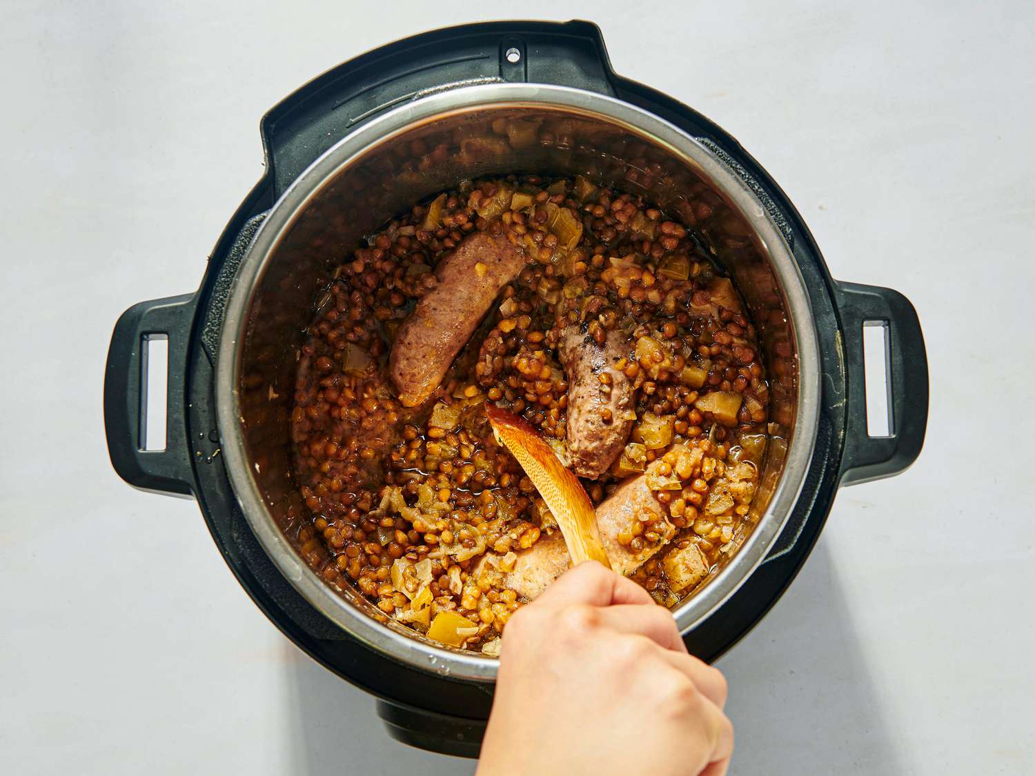 Stirring in vinegar into cooked lentils and sausage 