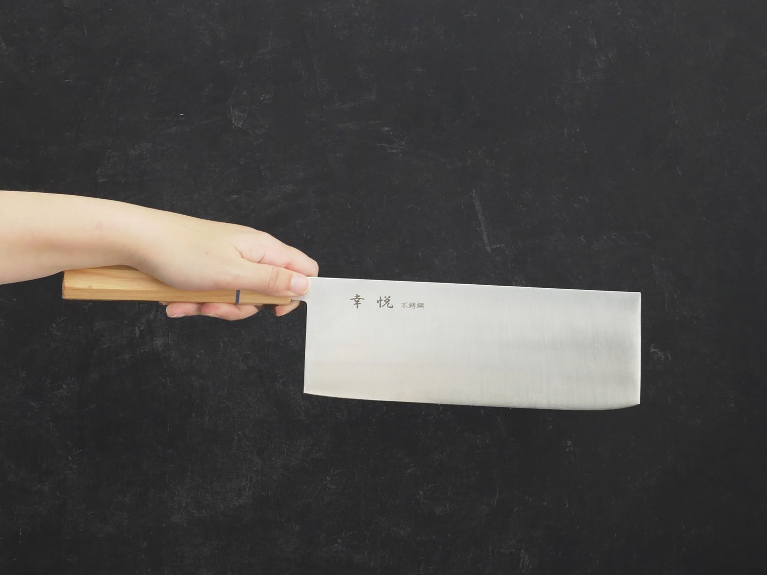 a hand holding a Chinese cleaver with a long handle