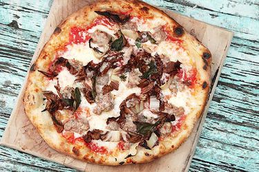Overhead view of Sausage and Radicchio Pizza on a cutting board, laid atop a distressed wood surface that was once painted powder blue.
