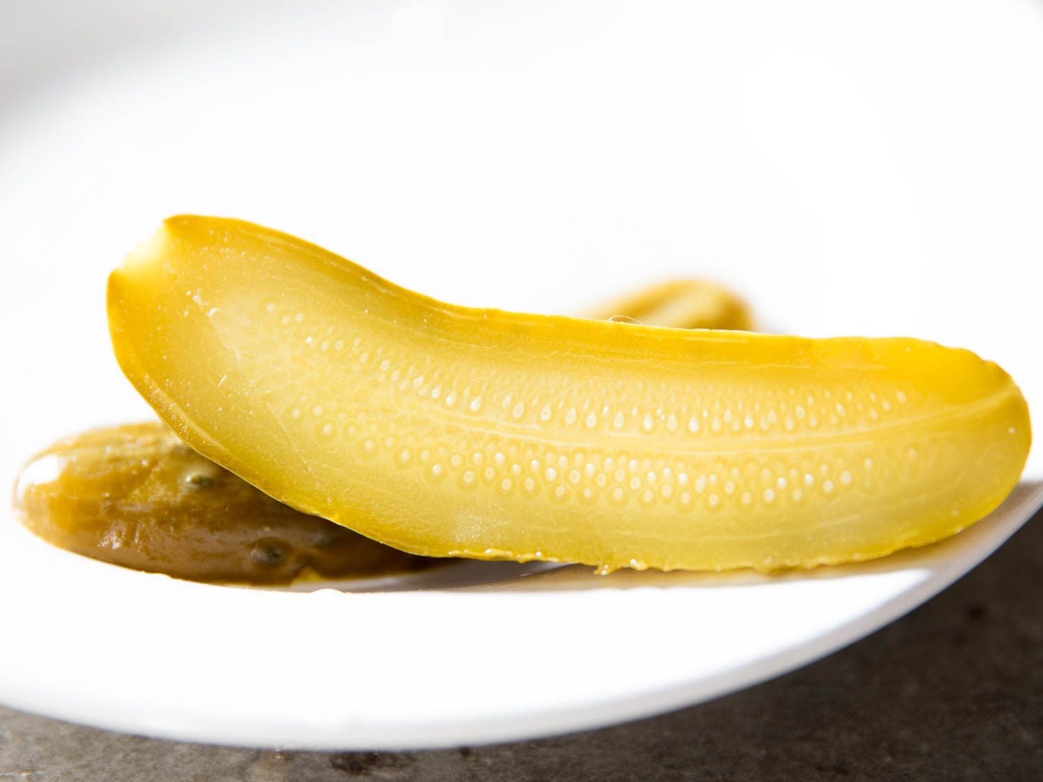 Homemade pickle sliced in half, resting on a plate.