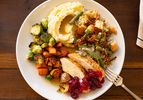 A Thanksgiving dinner plate consisting of mashed potatoes roasted vegetables stuffing turkey with cranberry sauce and a fork