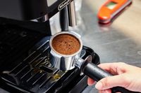 Person's hand holding up the portafilter that will go into the De'Longhi Stilosa Espresso Machine