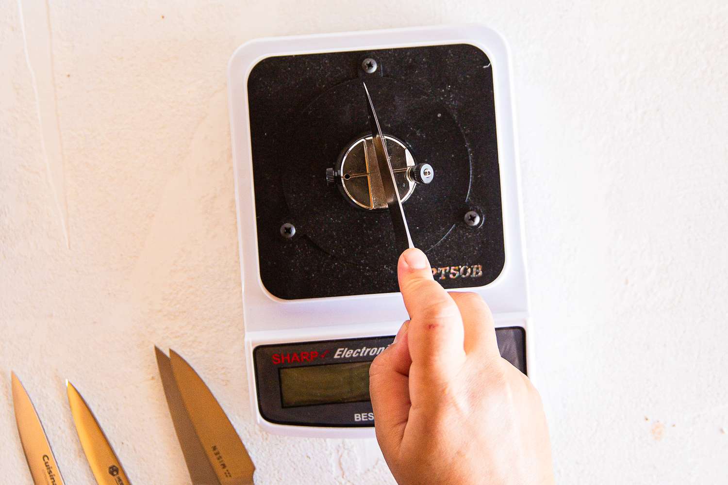 A hand holding a knife being tested on a knife sharpness reader