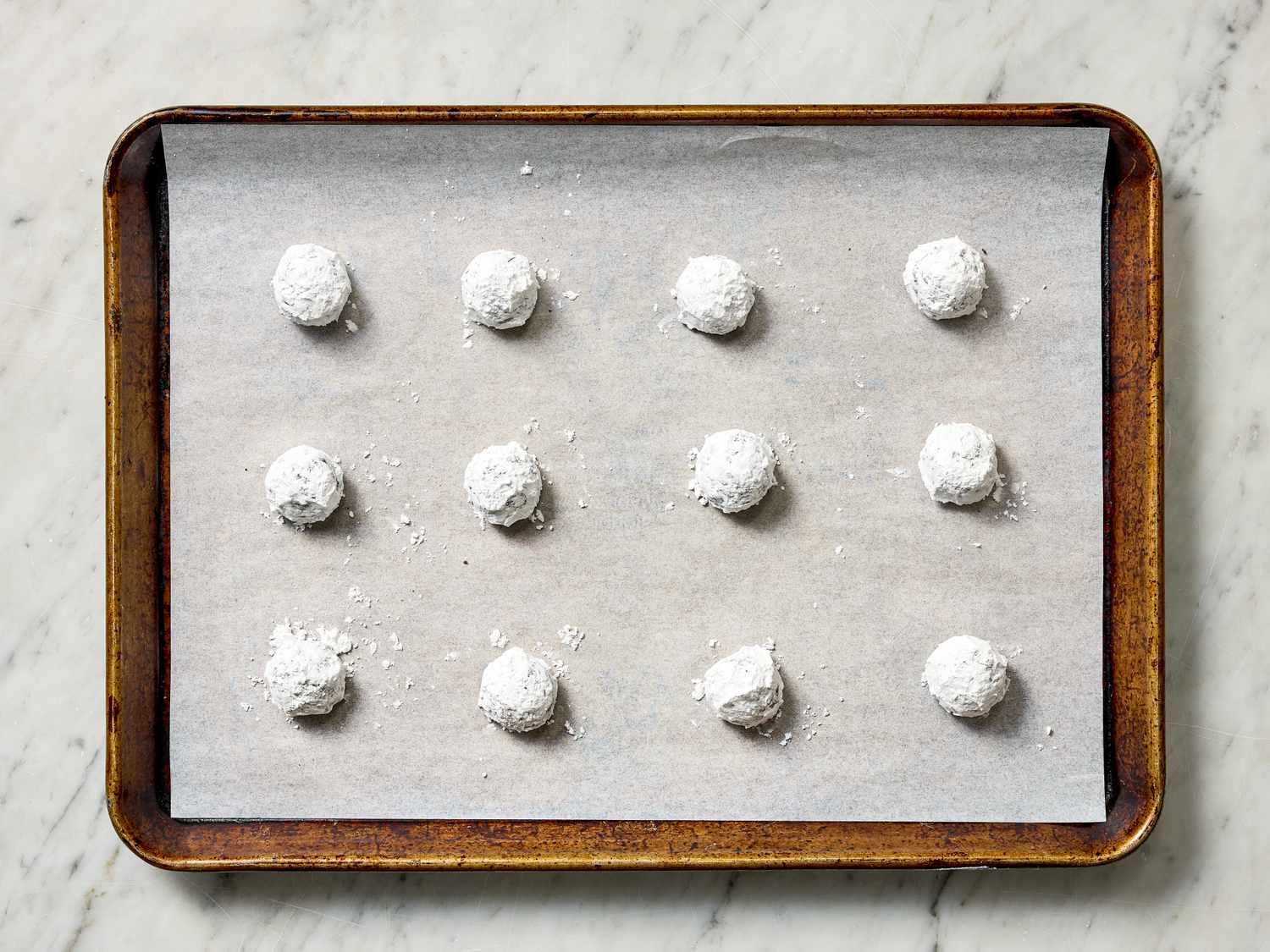 Unbaked powdered dough balls on a parchmentlined baking sheet