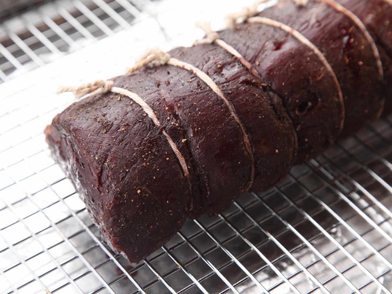 Beef tenderloin roast resting on rack in rimmed baking sheet