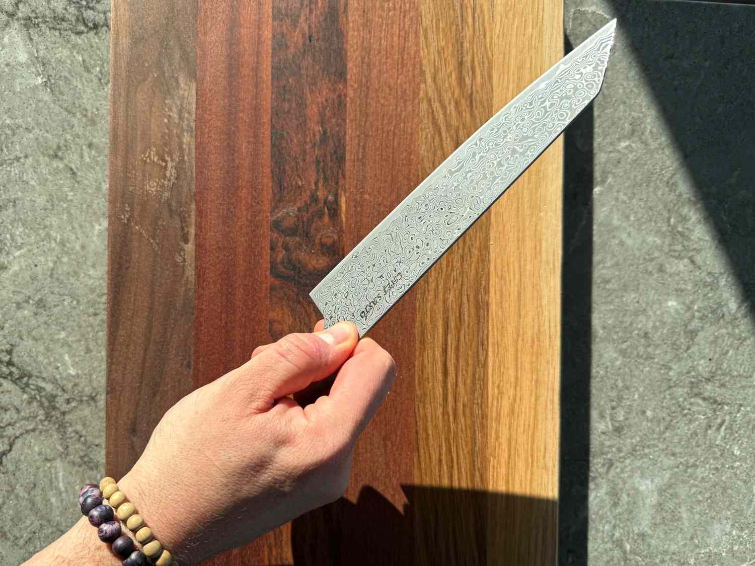 A hand holding a knife over a wooden surface