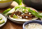 Braised Lamb Shoulder With Dried Chiles and Dates, served as a taco with cotija, avocado, radish slices, and a quartered hakurei turnip and its green top.