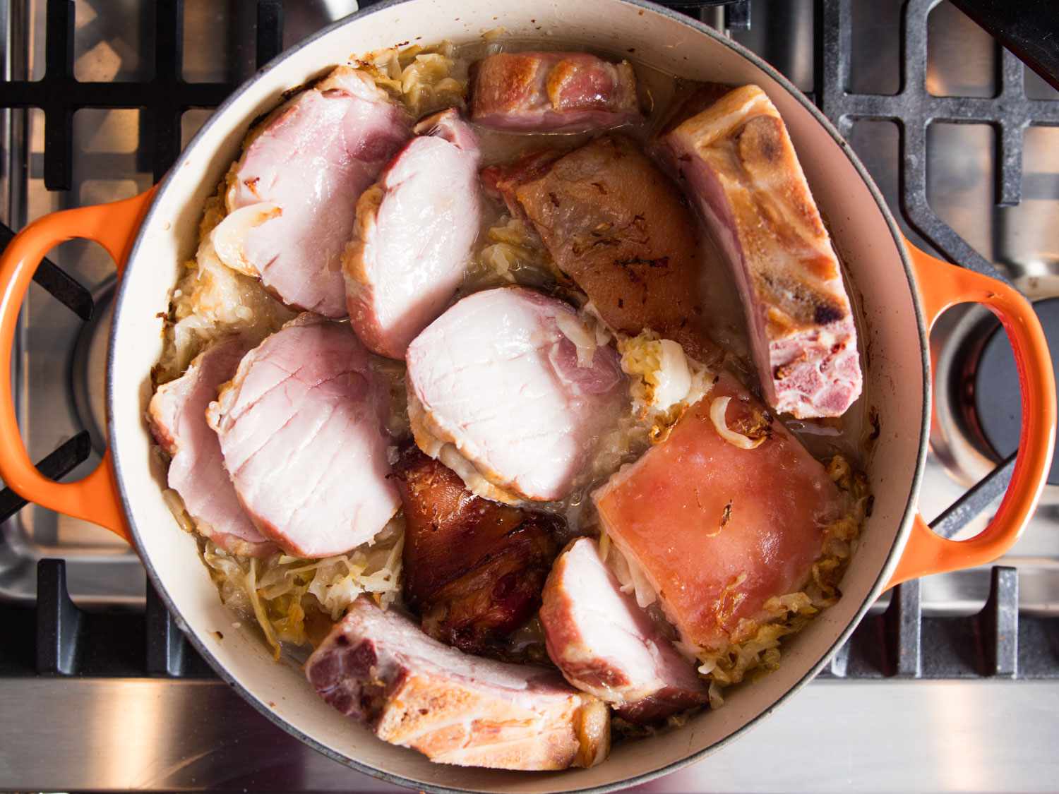 Overhead shot of the Dutch oven with all of the meats added to a pot of choucroute garnie.