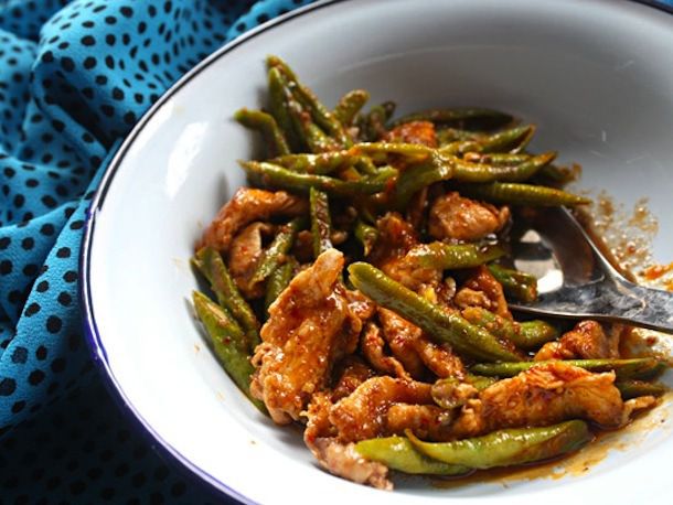 A bowl of red curry chicken stir-fry with green beans.