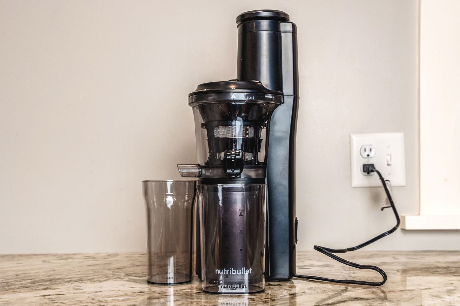A fully assembled black Nutribullet juicer plugged into an electrical outlet