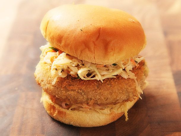  A Crispy Fried Chickpea Cake and Slaw Sandwich on a wooden board.