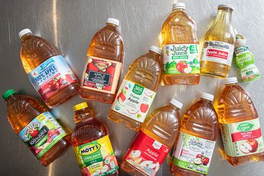 Various brands of apple juice bottles arranged on a metal surface