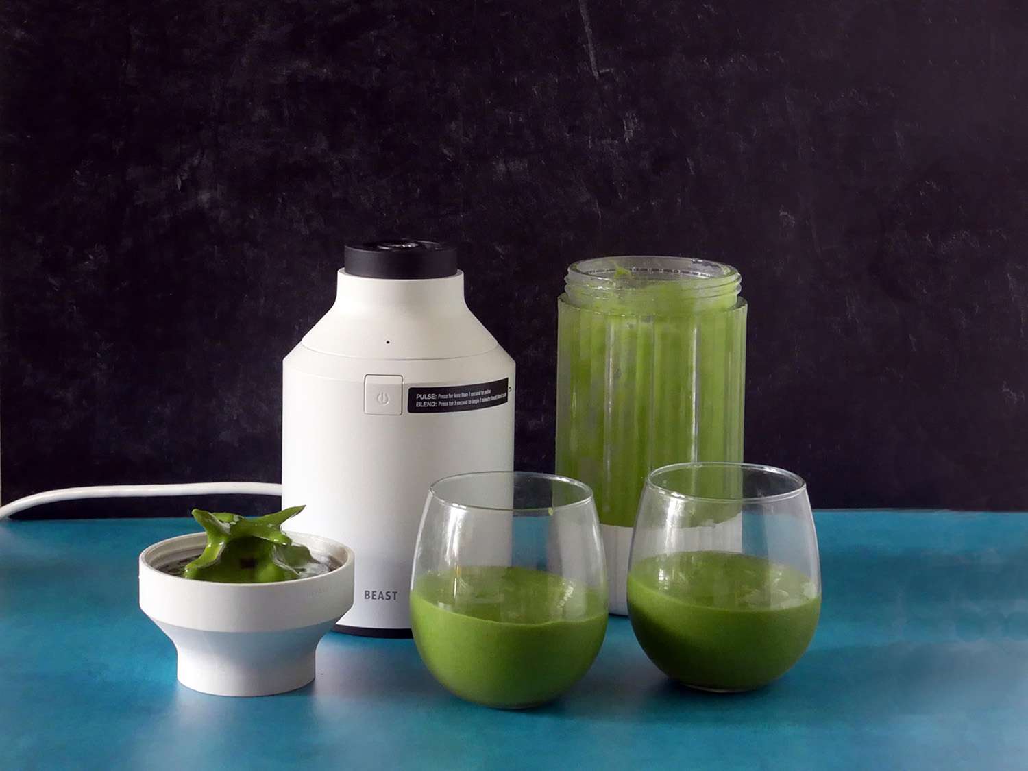 beast blender with two glasses with a kale smoothie in them.