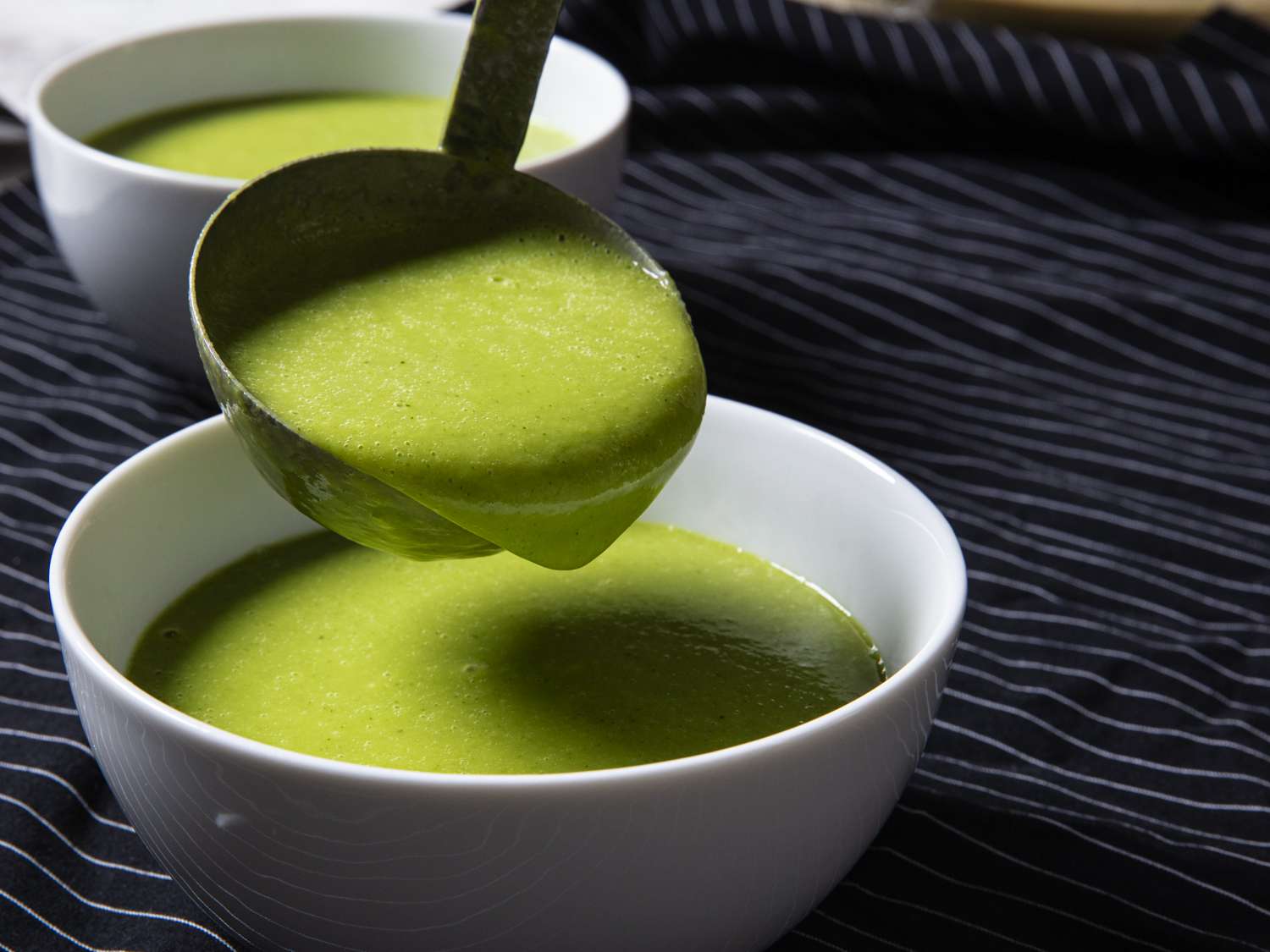 Creamy garlic scape soup being laddled into a bowl