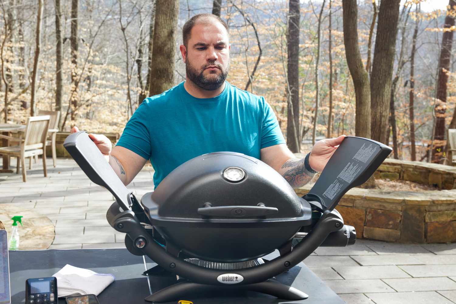 A person closing the wings of a portable gas grill.