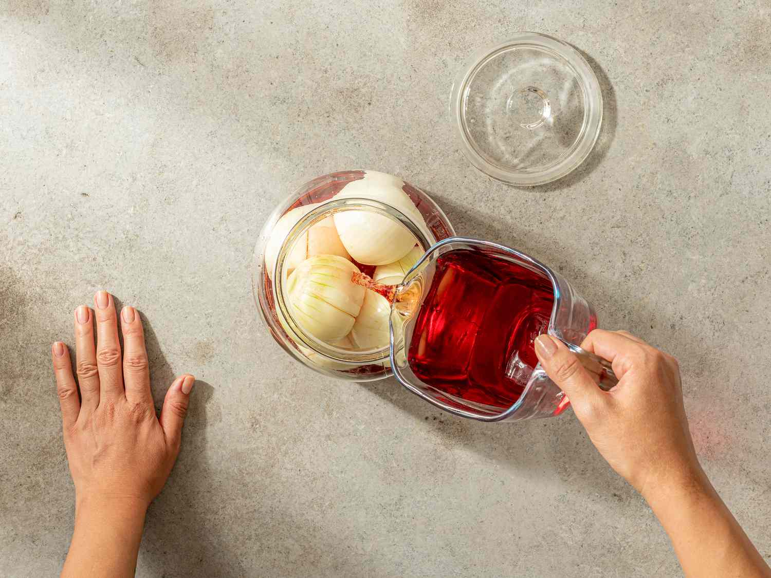 Overhead view of submerging onions with red wine vingar