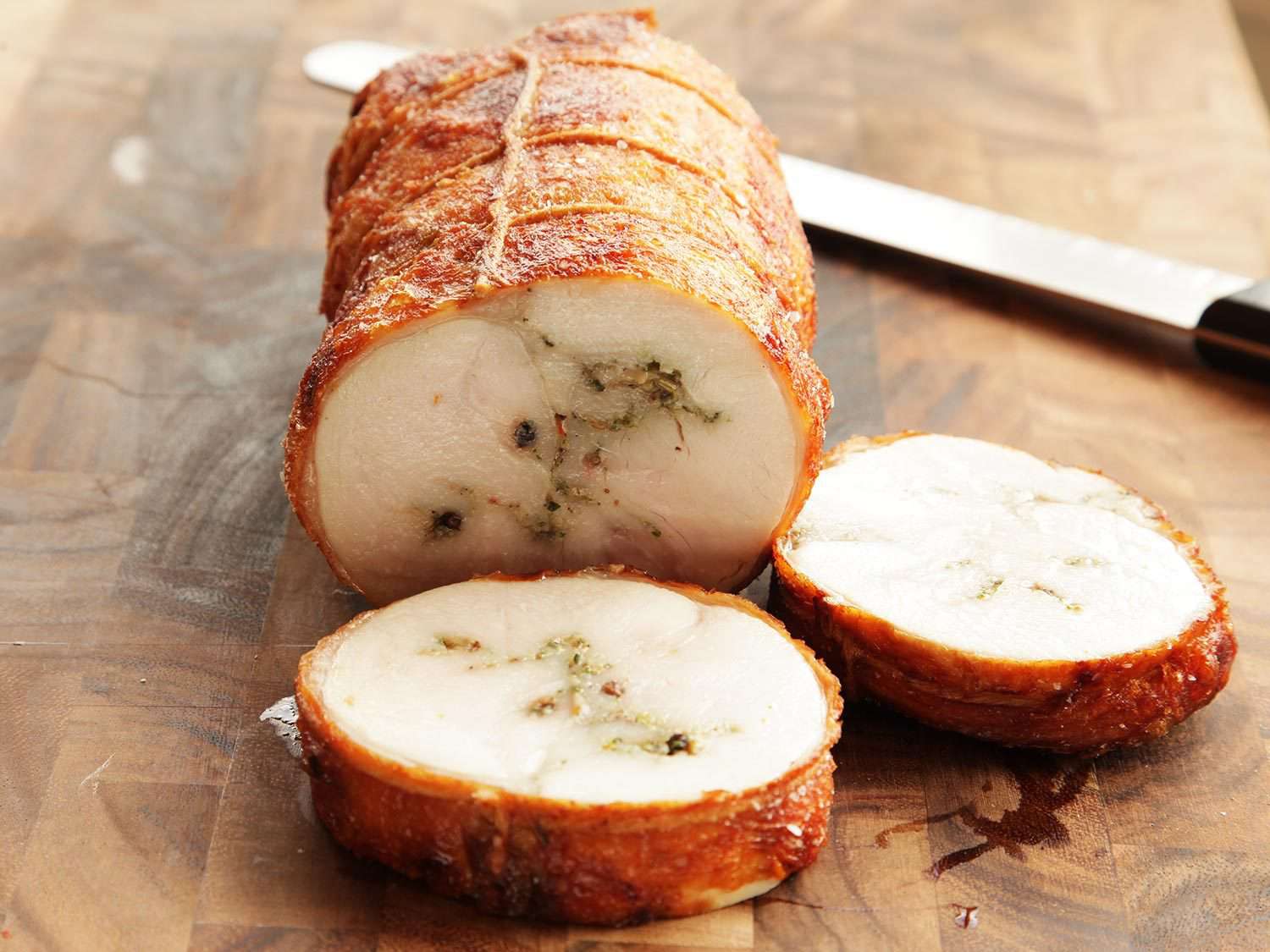 Sliced turkey porchetta on serving board.