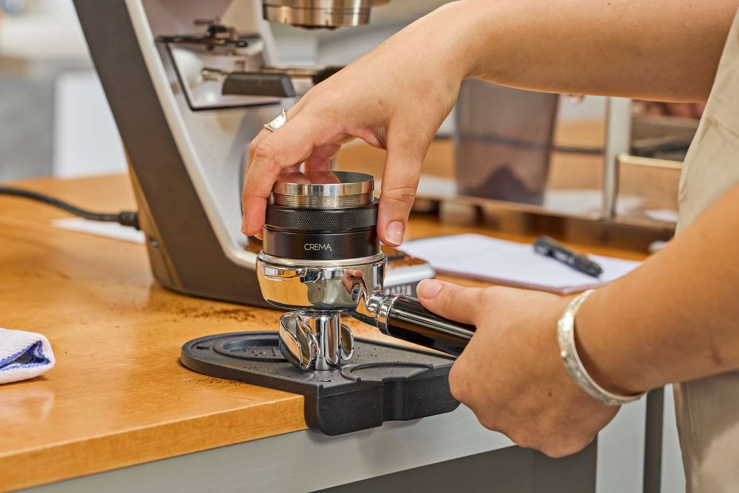 A person leveling coffee beans in the portafilter of the Lelit MaraX Espresso Machine PL62X-120