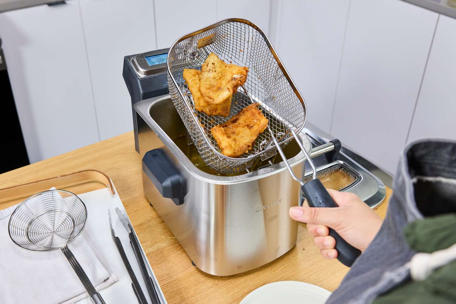 A person frying battered food in the Breville BDF500XL Smart Fryer
