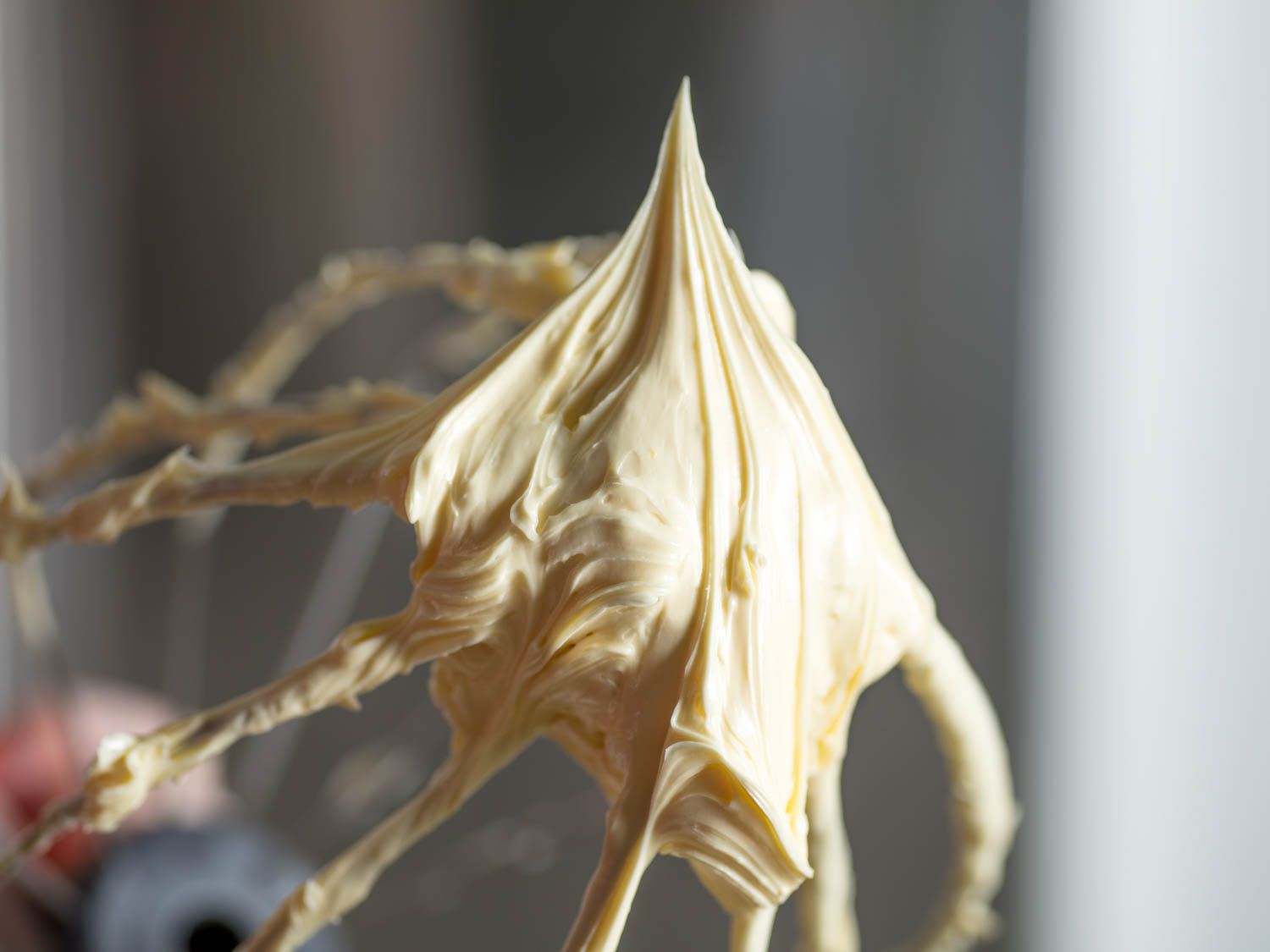 A closeup look at buttercream on a stand mixer's whisk