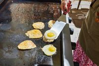 A person cooks eggs on the Weber 36 Inch Gas Griddle