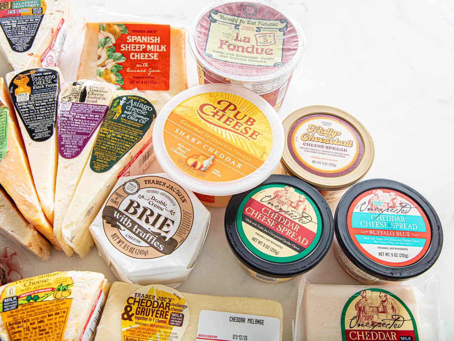 An assortment of Trader Joes brand cheeses and cheeserelated products displayed on a surface