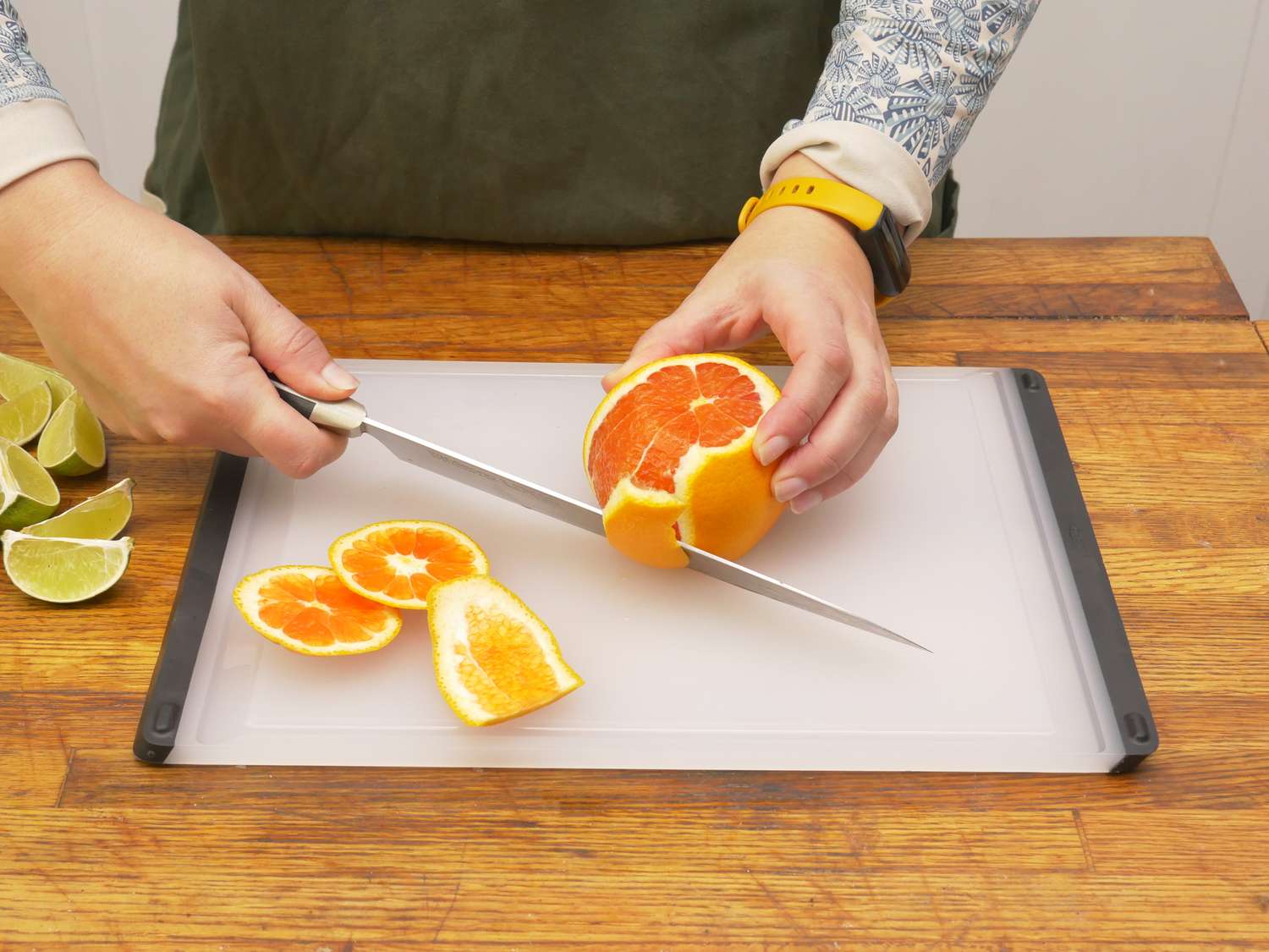 a person slicing the peel from an orange on the oxo cutting board