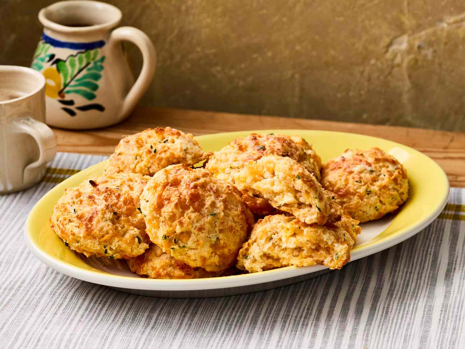 A plate of cheddar biscuits served on a striped tablecloth