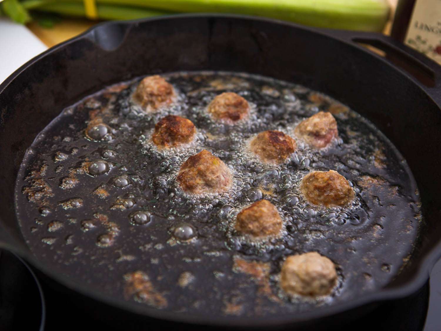 Swedish meatballs frying in a cast iron skillet. 