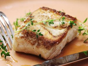 Butter-based sous vide and seared halibut with a sprig of thyme on top. 